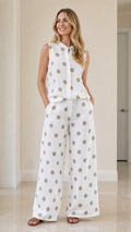 Woman wearing white polka dot sleeveless top and wide-leg pants set, front view